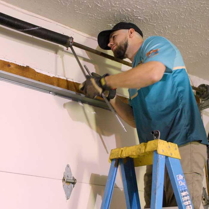 An Ohio Garage Door Repair technician is using sidewinder tool while installing a new garage door spring near Brooklyn, OH